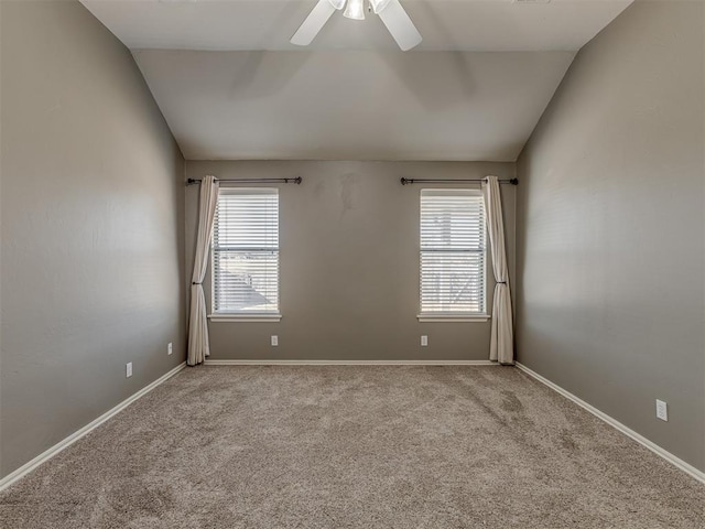 empty room with ceiling fan, a healthy amount of sunlight, lofted ceiling, and light colored carpet