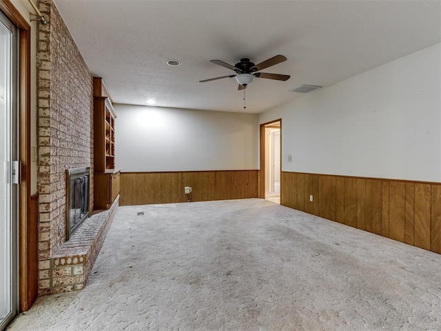 7000 N Libby Ave, Oklahoma City, OK 73132 - unfurnished living room with a brick fireplace, a textured ceiling, wooden walls, carpet floors, and ceiling fan