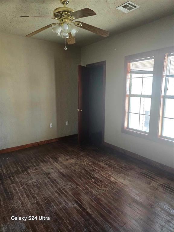 interior space featuring ceiling fan, dark wood-type flooring, and a textured ceiling