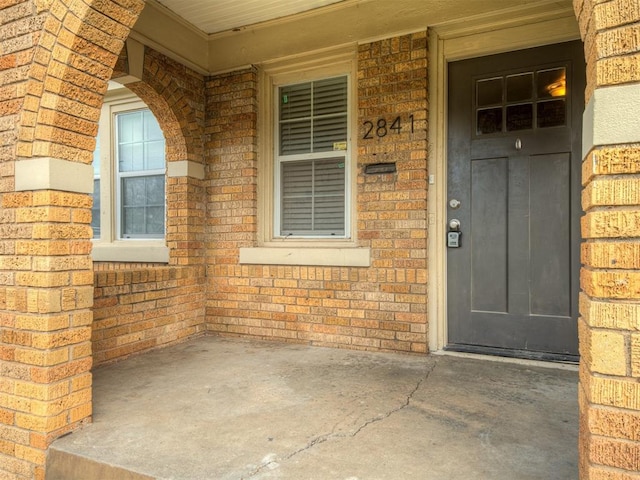 entrance to property featuring brick siding and a porch