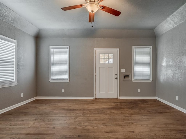 entryway with lofted ceiling, a ceiling fan, wood finished floors, baseboards, and a textured wall