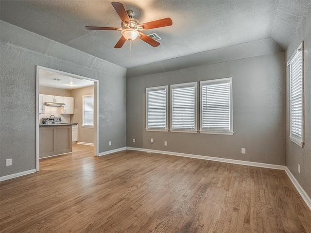 spare room featuring a wealth of natural light, baseboards, and light wood finished floors