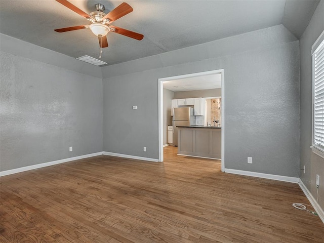 interior space featuring visible vents, baseboards, wood finished floors, and a ceiling fan