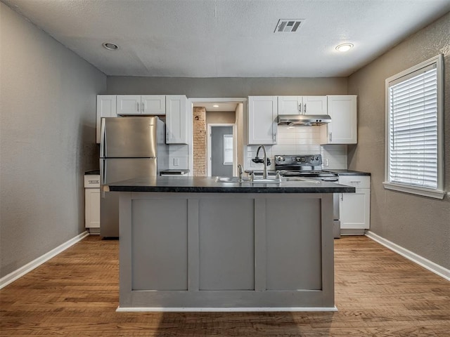 kitchen featuring under cabinet range hood, dark countertops, appliances with stainless steel finishes, and white cabinetry