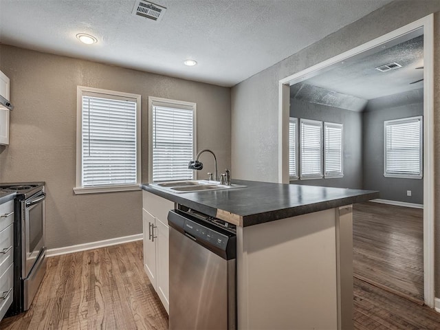 kitchen featuring dark countertops, visible vents, appliances with stainless steel finishes, and a sink