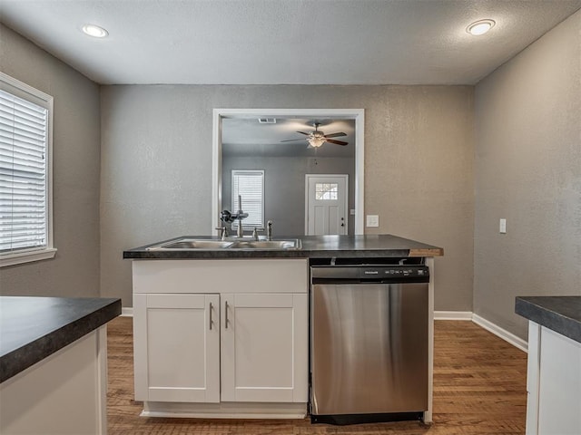 kitchen with stainless steel dishwasher, dark countertops, and wood finished floors