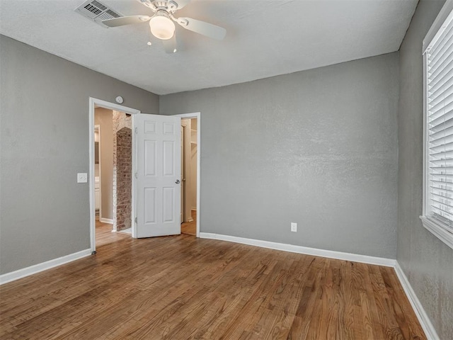 unfurnished bedroom featuring a ceiling fan, wood finished floors, baseboards, and a textured wall