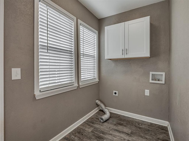 laundry area featuring electric dryer hookup, baseboards, dark wood-type flooring, and cabinet space