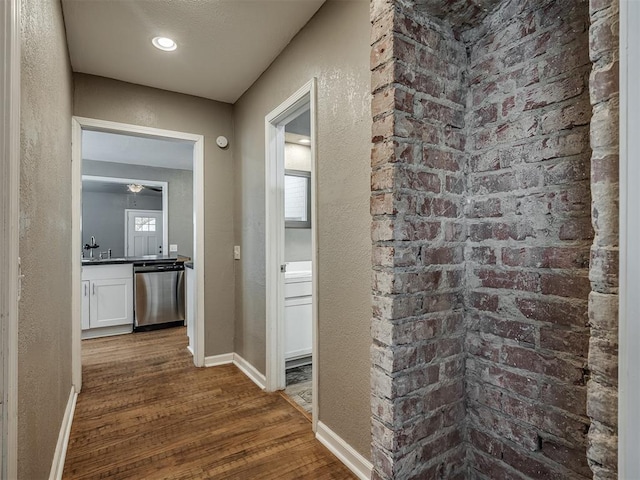 hall with wood finished floors, baseboards, and a textured wall