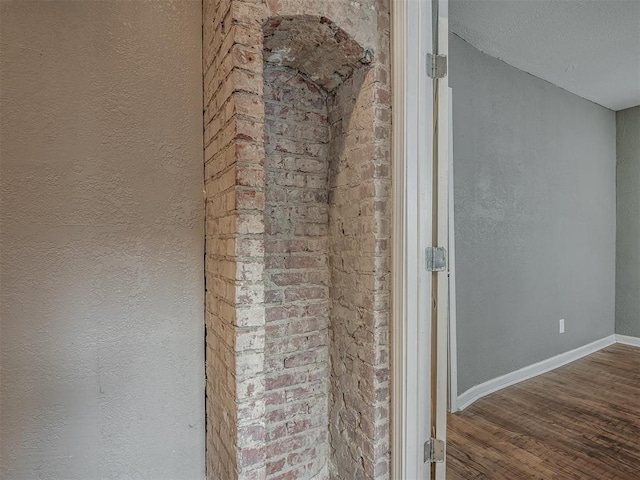 room details with baseboards, wood finished floors, and a textured wall