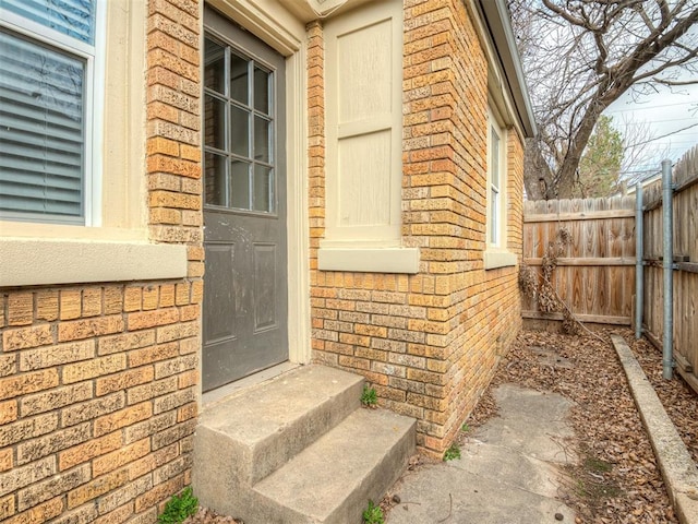 property entrance with brick siding and fence