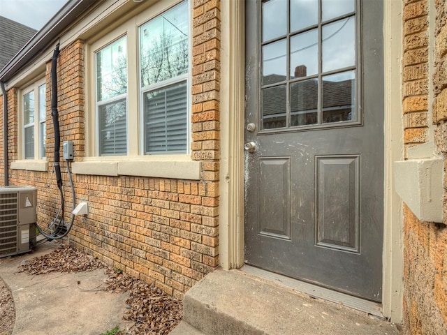 doorway to property featuring central air condition unit and brick siding