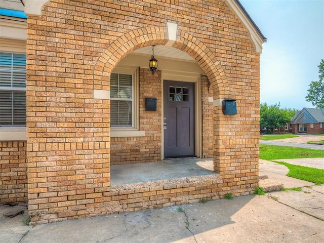 view of exterior entry featuring brick siding