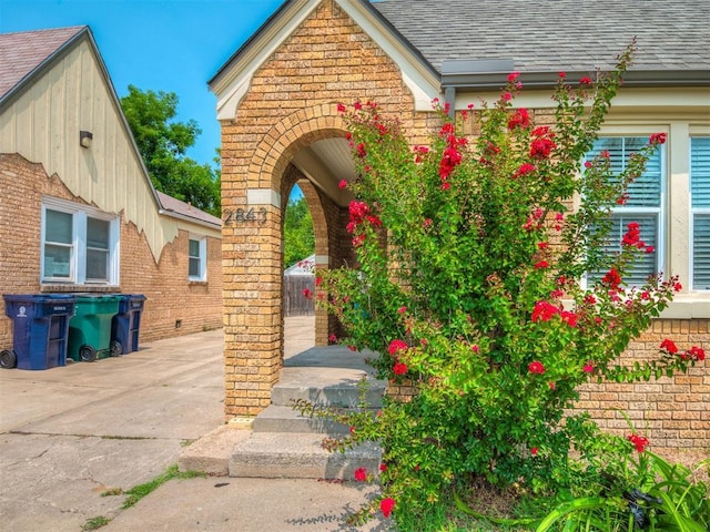 exterior space featuring brick siding and a shingled roof