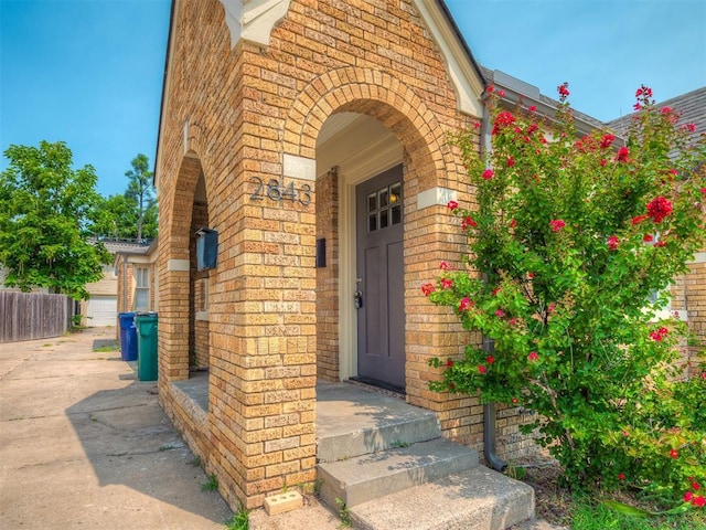 doorway to property with fence and brick siding