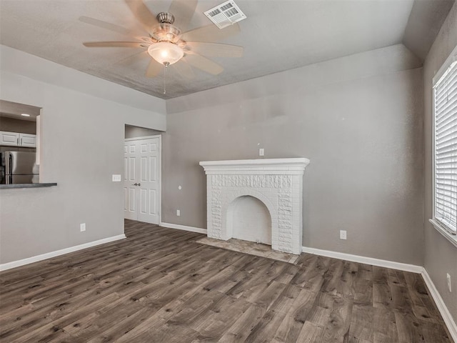 unfurnished living room featuring wood finished floors, visible vents, baseboards, a fireplace, and ceiling fan