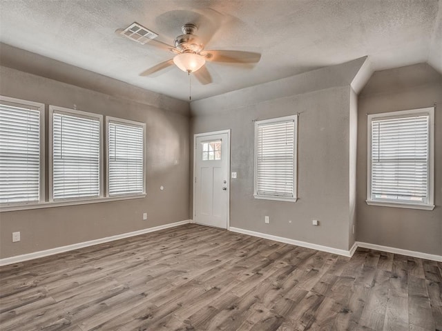 foyer with baseboards, wood finished floors, visible vents, and a textured ceiling