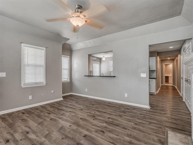 spare room featuring dark wood finished floors, baseboards, and ceiling fan