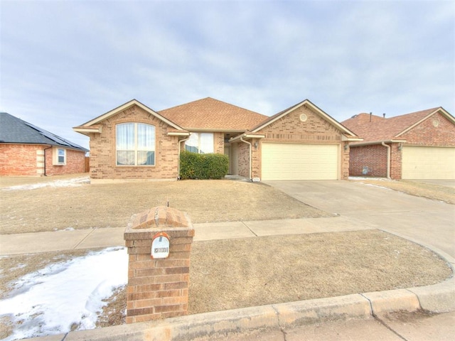 ranch-style home featuring a garage, concrete driveway, brick siding, and a shingled roof