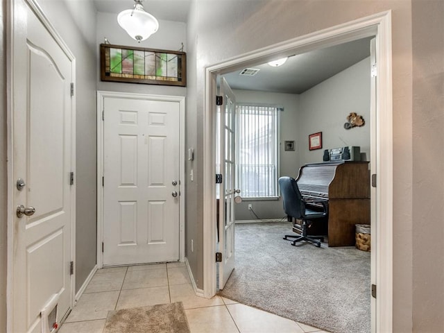 entryway featuring light carpet, baseboards, visible vents, and light tile patterned flooring