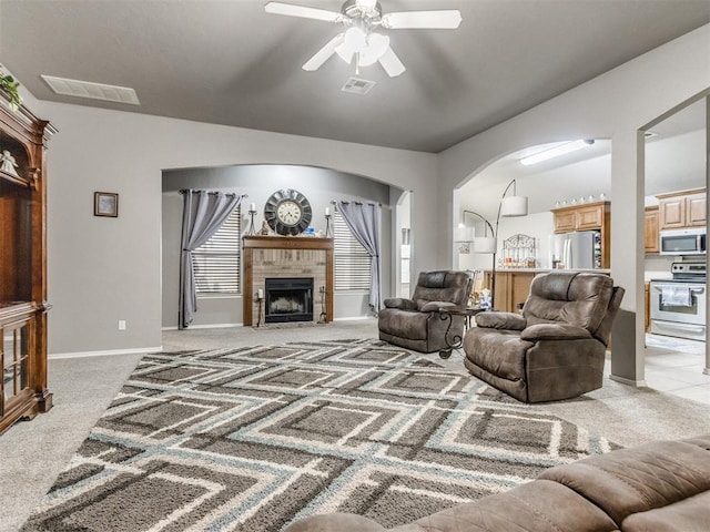 living room with a ceiling fan, visible vents, a fireplace, and light carpet