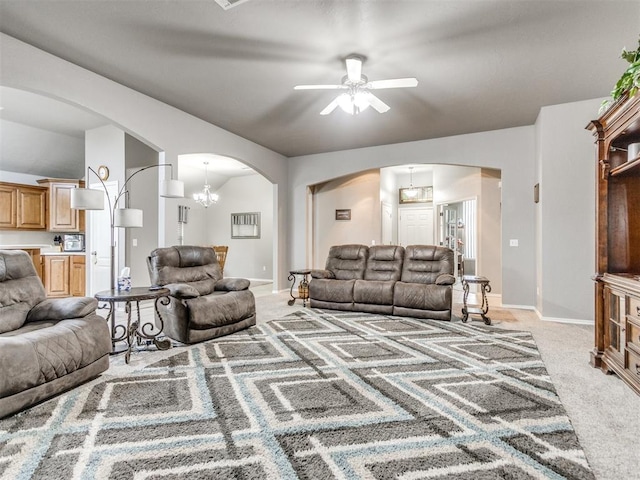 living area with arched walkways, ceiling fan with notable chandelier, baseboards, and light colored carpet