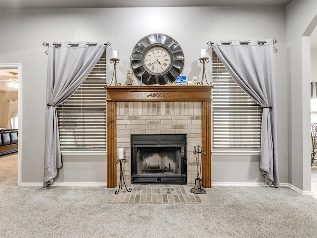 interior space featuring carpet floors, a brick fireplace, baseboards, and arched walkways