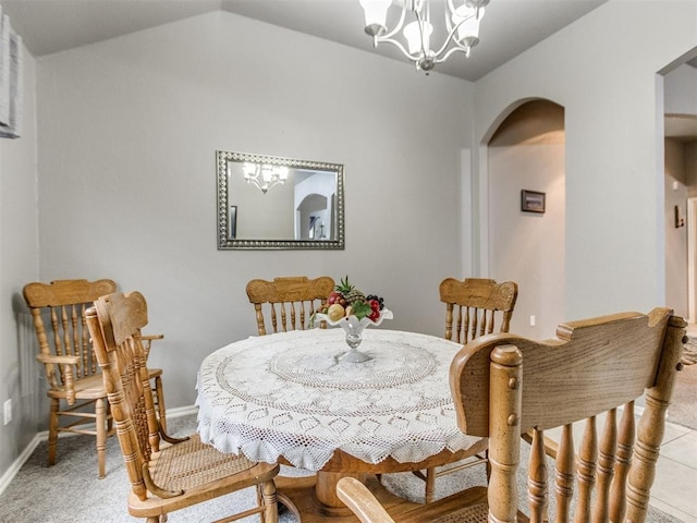 dining space with arched walkways, a notable chandelier, light carpet, baseboards, and vaulted ceiling