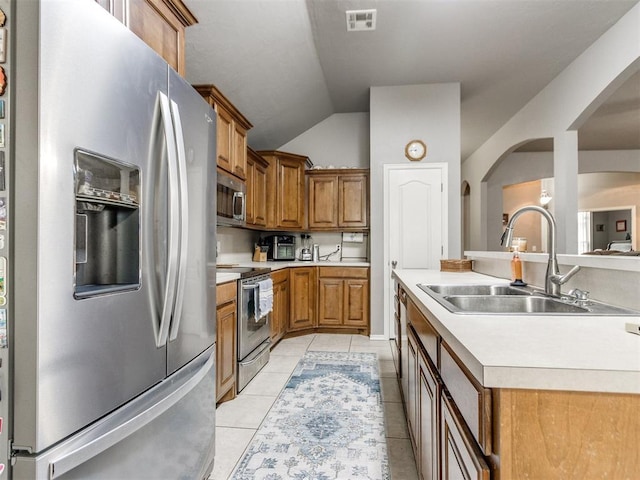 kitchen featuring stainless steel appliances, a sink, visible vents, light countertops, and brown cabinetry