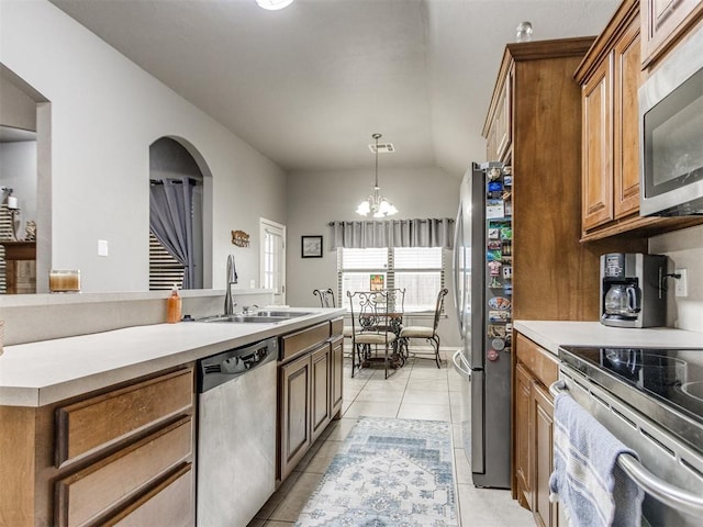 kitchen with stainless steel appliances, brown cabinetry, light countertops, and a sink