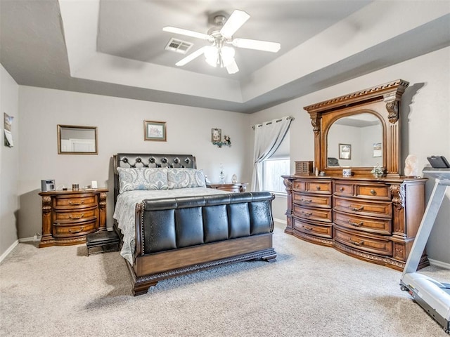 bedroom with a raised ceiling, carpet flooring, visible vents, and baseboards