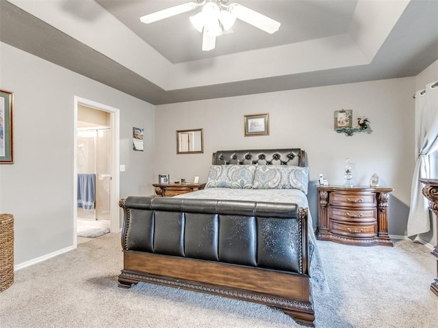 bedroom featuring baseboards, a ceiling fan, ensuite bath, a tray ceiling, and carpet floors