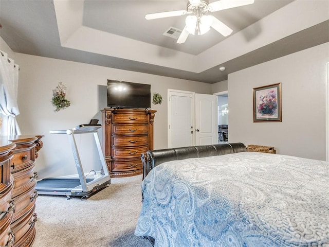 bedroom featuring a raised ceiling, light colored carpet, and ceiling fan