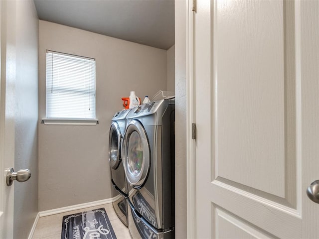 washroom with laundry area, baseboards, washing machine and clothes dryer, and light tile patterned floors