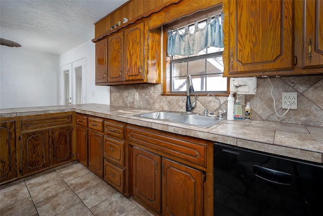 kitchen with sink, black dishwasher, a textured ceiling, tile counters, and tasteful backsplash