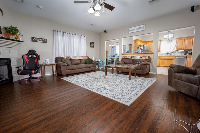 living room with ceiling fan, dark hardwood / wood-style floors, and a tile fireplace