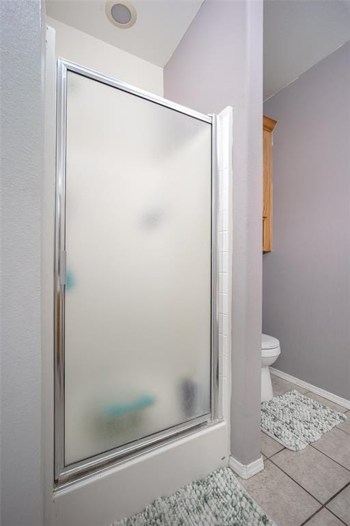 bathroom with combined bath / shower with glass door, tile patterned floors, and toilet