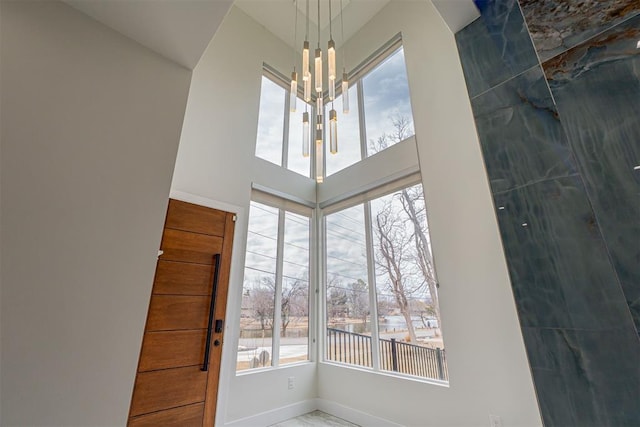 foyer entrance with a notable chandelier, a healthy amount of sunlight, and a high ceiling