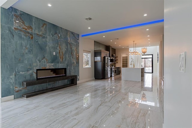 unfurnished living room with a tiled fireplace, a chandelier, and sink