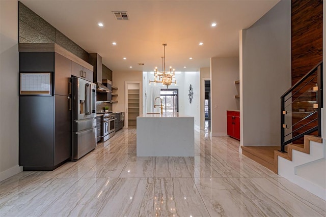 kitchen featuring pendant lighting, sink, a kitchen island with sink, stainless steel appliances, and an inviting chandelier