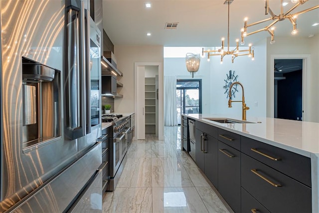 kitchen with appliances with stainless steel finishes, sink, hanging light fixtures, a large island with sink, and wall chimney exhaust hood