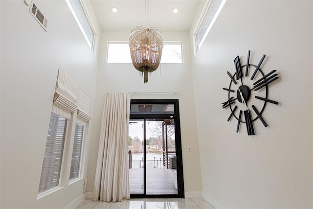 foyer entrance with a high ceiling, a healthy amount of sunlight, and an inviting chandelier