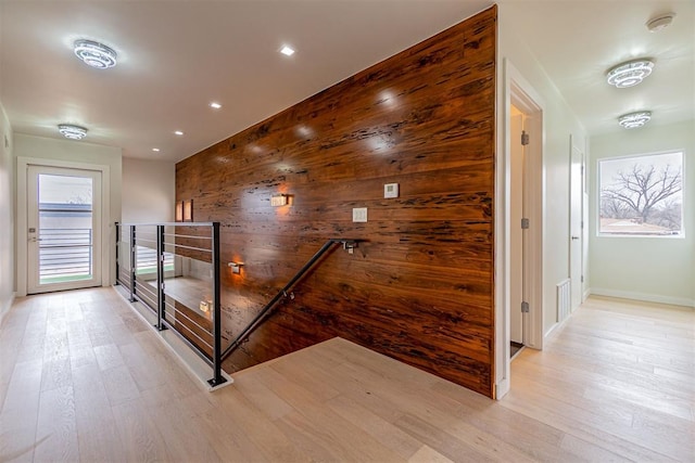 corridor with light hardwood / wood-style flooring and wood walls