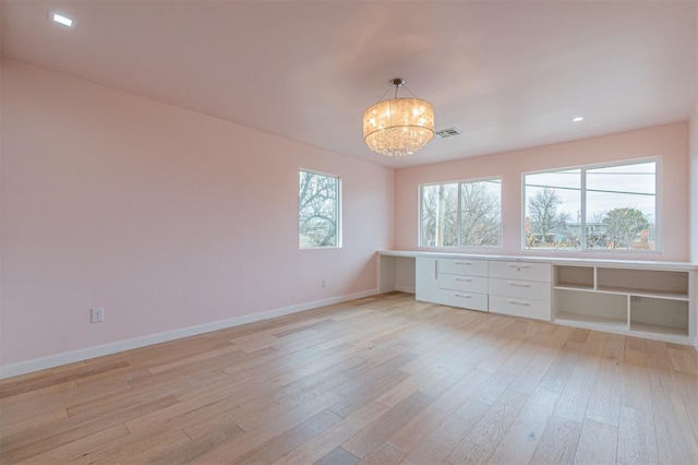 unfurnished room featuring a chandelier and light wood-type flooring