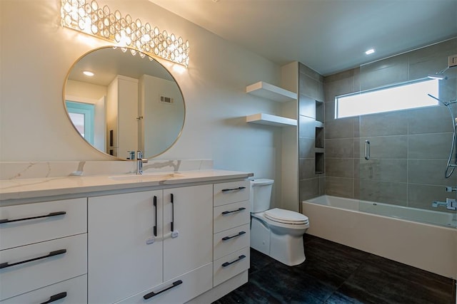 full bathroom with tiled shower / bath, vanity, and toilet