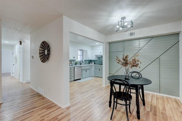 dining area with sink, a textured ceiling, and light wood-type flooring