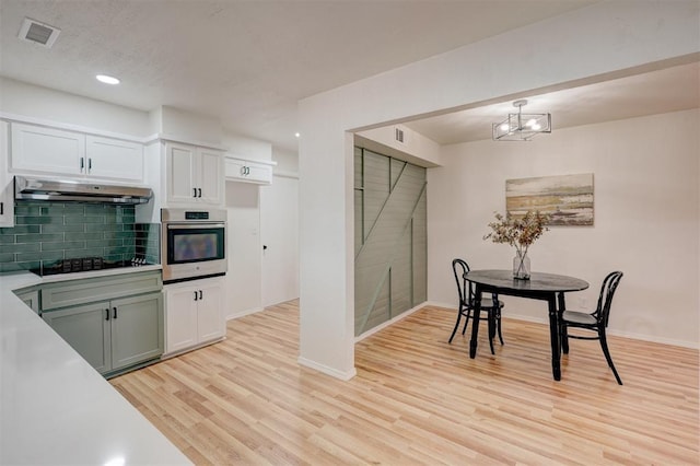 kitchen featuring black electric cooktop, white cabinetry, decorative light fixtures, and oven