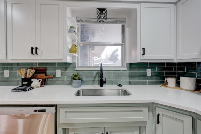 kitchen with tasteful backsplash, stainless steel dishwasher, sink, and white cabinets