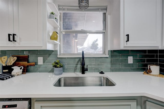 kitchen featuring tasteful backsplash, sink, dishwasher, and white cabinets