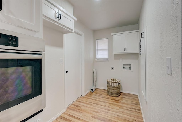 washroom with cabinets, electric dryer hookup, washer hookup, and light hardwood / wood-style flooring